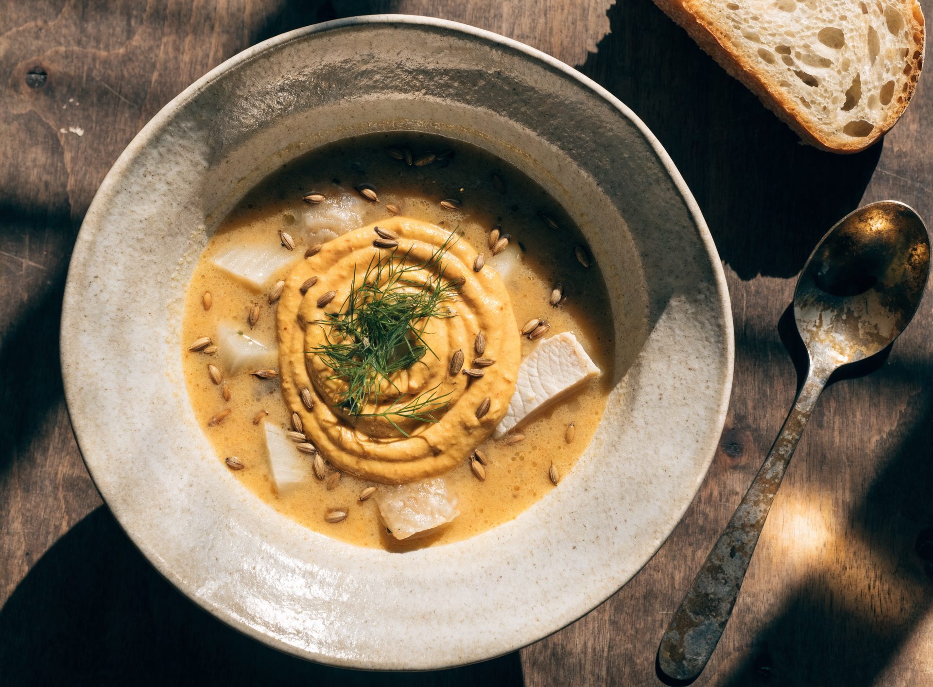 Tiefe Schale Fenchel-Fischsuppe mit Senfmayo-Tupfer, frischer Dill, dunkles Brot daneben